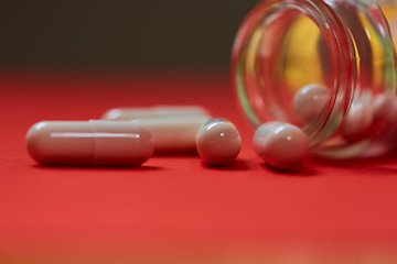 Image showing Pills spilling out of pill bottle on red. Top view with copy space. 