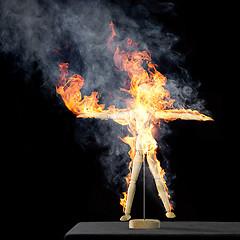 Image showing burning wooden doll on desktop