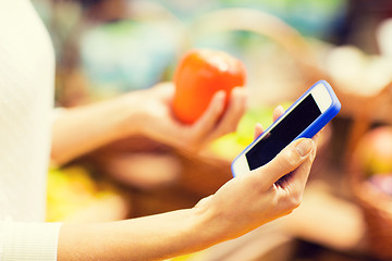 Image showing woman with smartphone and persimmon in market