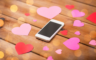Image showing close up of smartphone and hearts on wood