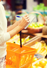 Image showing close up of woman writing to notepad in market