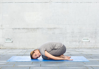 Image showing happy woman making yoga in child pose on mat