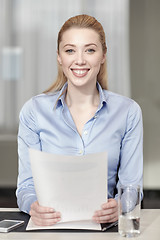 Image showing smiling woman holding papers in office