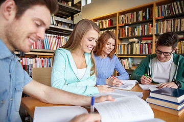 Image showing happy students writing to notebooks in library