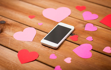 Image showing close up of smartphone and hearts on wood