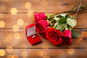 Image showing close up of diamond engagement ring and red roses