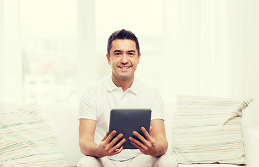 Image showing smiling man working with tablet pc at home