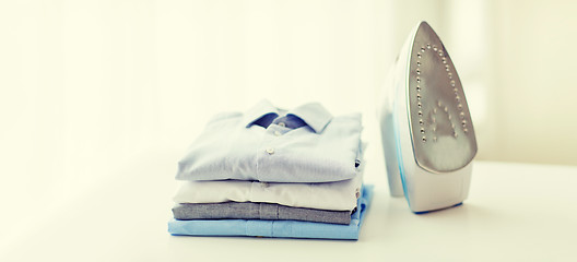 Image showing close up of iron and clothes on table at home