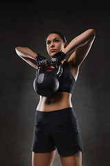 Image showing young woman flexing muscles with kettlebell in gym