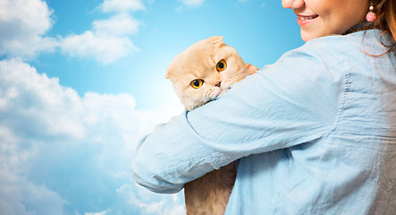 Image showing happy woman holding scottish fold cat over sky