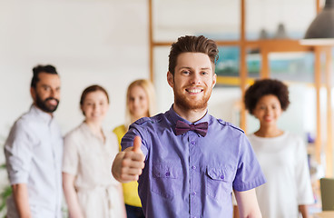 Image showing happy man showing thumbs up over team in office