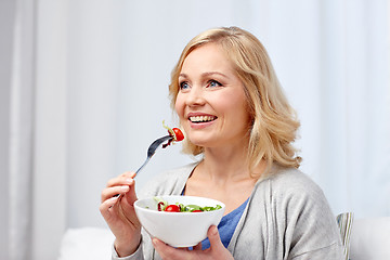 Image showing smiling middle aged woman eating salad at home