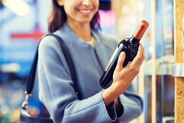 Image showing happy woman choosing and buying wine in market