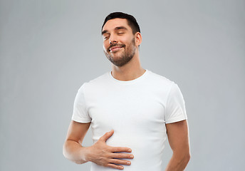 Image showing happy full man touching tummy over gray background