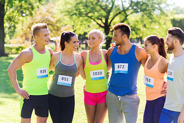 Image showing happy friends or couple with racing badge numbers