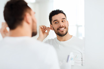 Image showing man cleaning ear with cotton swab at bathroom