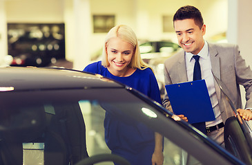 Image showing happy woman with car dealer in auto show or salon