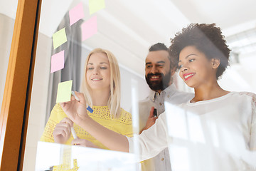 Image showing happy creative team writing on stickers at office