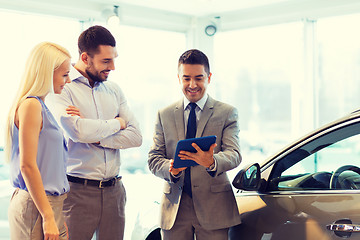 Image showing happy couple with car dealer in auto show or salon