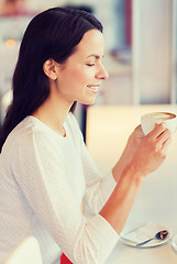 Image showing smiling young woman drinking coffee at cafe