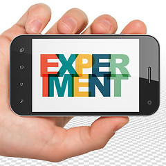 Image showing Science concept: Hand Holding Smartphone with Experiment on  display