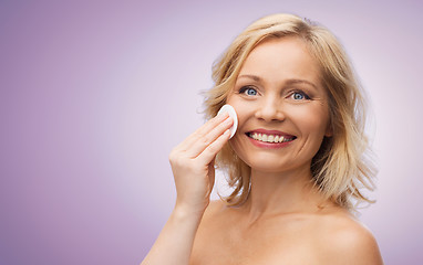 Image showing happy woman cleaning face with cotton pad