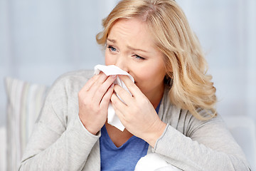 Image showing ill woman blowing nose to paper napkin