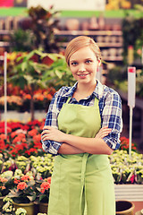 Image showing happy woman with flowers in greenhouse