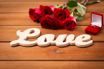 Image showing close up of diamond ring, red roses and word love