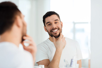 Image showing happy young man looking to mirror at home bathroom