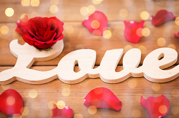 Image showing close up of word love cutout with red rose on wood