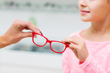Image showing close up of girl taking glasses at optics store