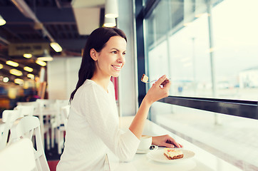 Image showing smiling young woman with cake and coffee at cafe