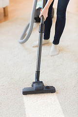 Image showing close up of woman legs with vacuum cleaner at home