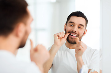 Image showing man with dental floss cleaning teeth at bathroom