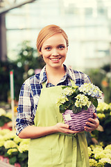 Image showing happy woman holding flowers in greenhouse