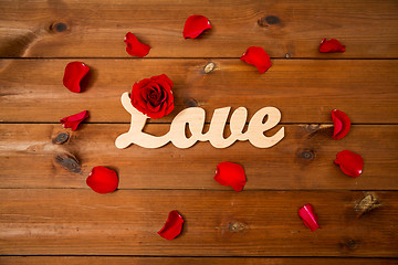 Image showing close up of word love cutout with red rose on wood