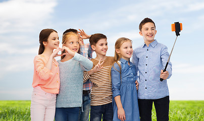 Image showing happy children with smartphone and selfie stick