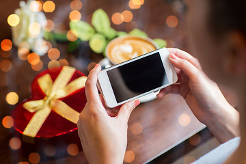 Image showing close up of hands with smartphone, gift and coffee