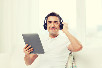 Image showing smiling man with tablet pc and headphones at home