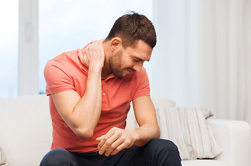 Image showing unhappy man suffering from neck pain at home