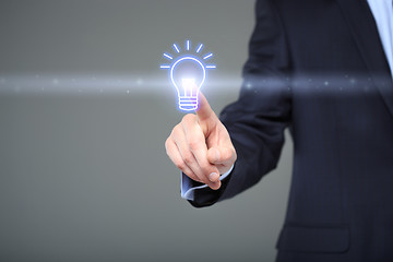 Image showing technology and internet concept - businessman pressing button with bulb on virtual screens