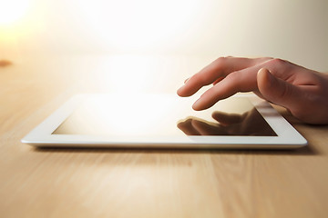 Image showing The tablet with the hand on wooden table