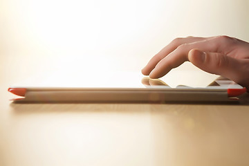 Image showing The tablet with the hand on wooden table