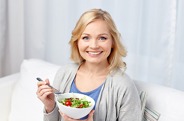 Image showing smiling middle aged woman eating salad at home