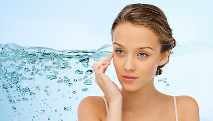 Image showing young woman applying cream to her face