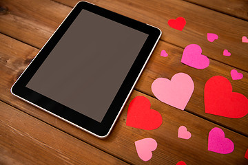 Image showing close up of tablet pc and hearts on wood