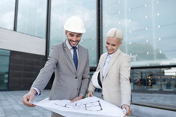 Image showing smiling businessmen with blueprint and helmets