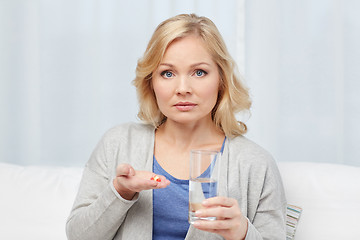 Image showing woman with medicine and water glass at home