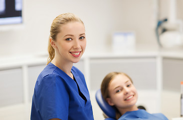 Image showing happy female dentist with patient girl at clinic